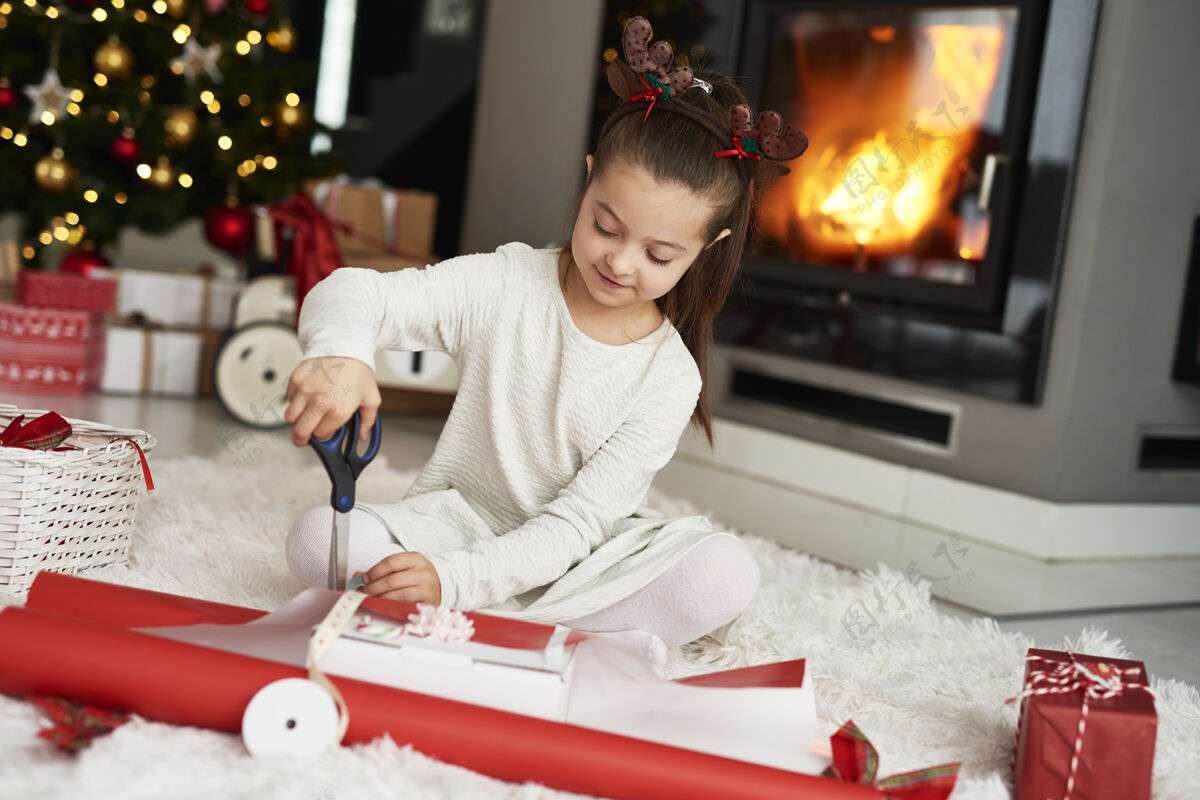 包装小女孩在打包圣诞礼物家居室内坐地毯