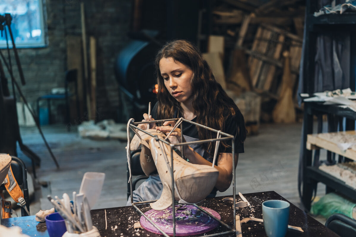工具在工作室里享受最喜爱工作的年轻女子的肖像波特小心地在泥鲸上工作制造车间陶器
