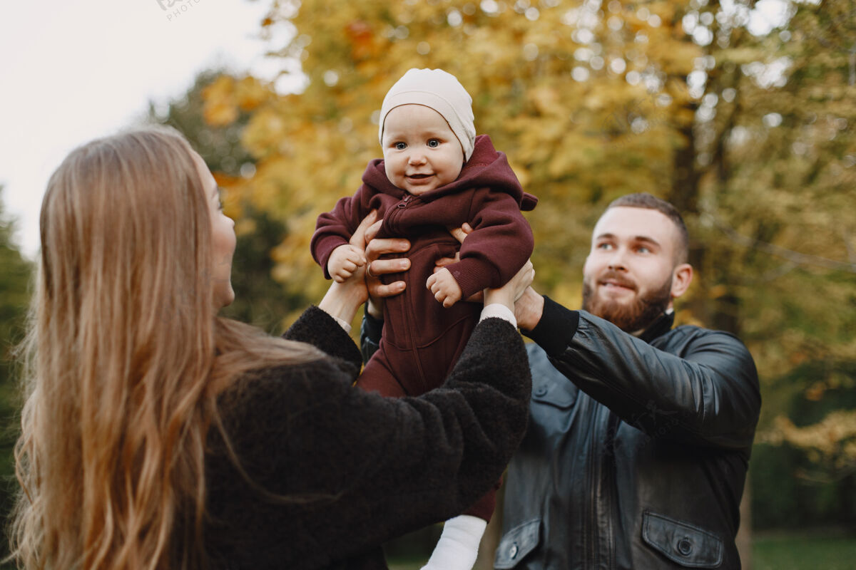 女儿一家人在秋天的公园里男人穿着黑色夹克可爱的小女孩和父母父母胡子年轻