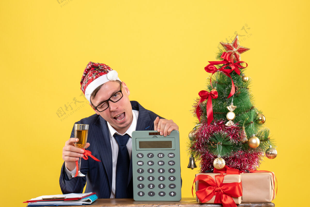 桌子商务人士坐在圣诞树旁的桌子旁敬酒 黄色的礼物生意人喜剧演员乐器