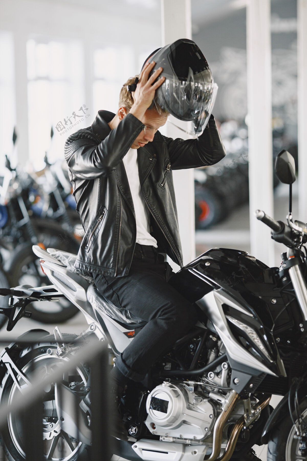 新一个男人在摩托店里选摩托车一个穿黑夹克的男人一个戴头盔的男人购买服务帅气