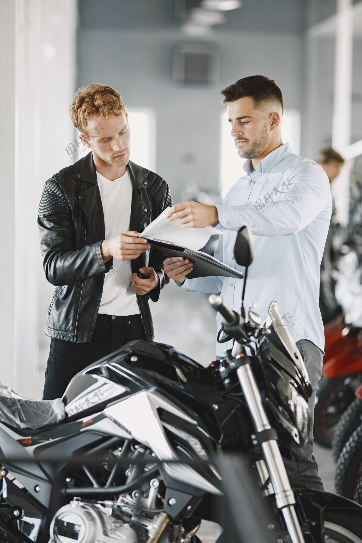 车辆男人在摩托店里选摩托车穿黑色夹克的家伙经理和客户在一起商店摩托车经销商