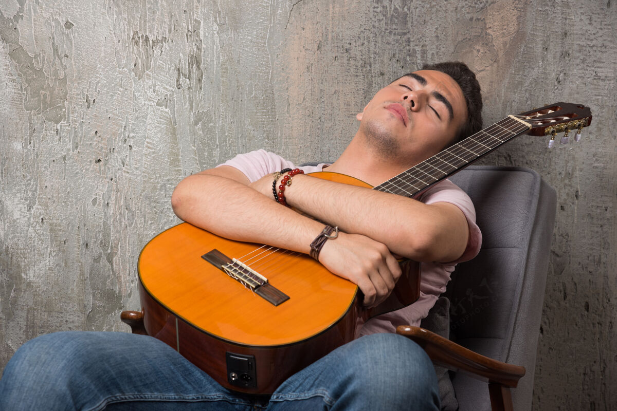 肖像帅哥拿着吉他睡在椅子上黑发男人休闲