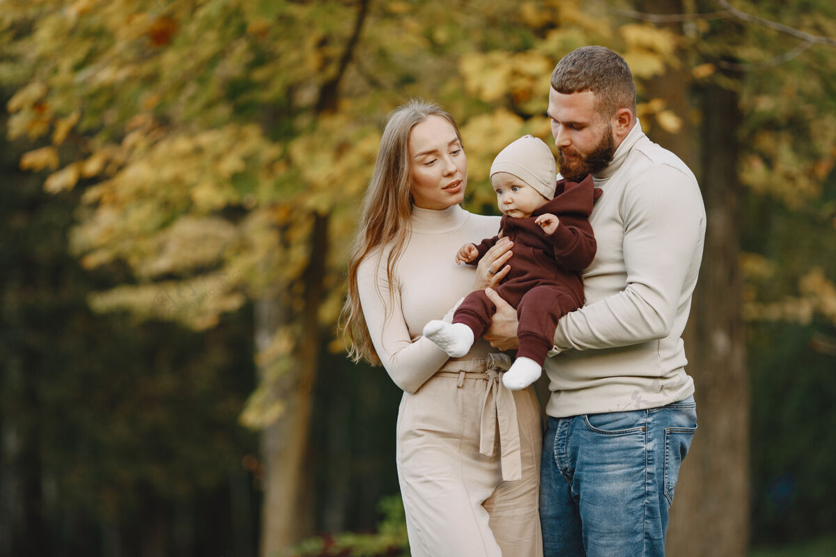 女儿秋天公园里的一家人穿棕色毛衣的男人和父母在一起的可爱小女孩父亲毛衣户外