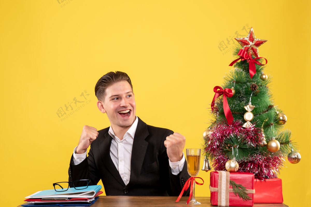 圣诞树前视图年轻的男工人坐在圣诞礼物和圣诞树新郎情绪男