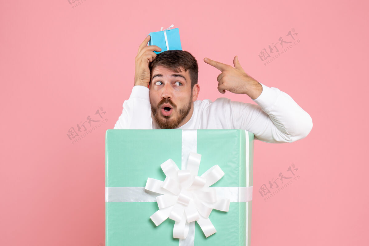 盒子礼物盒内年轻人的正面图 粉红色的墙上挂着小礼物快乐信封粉色