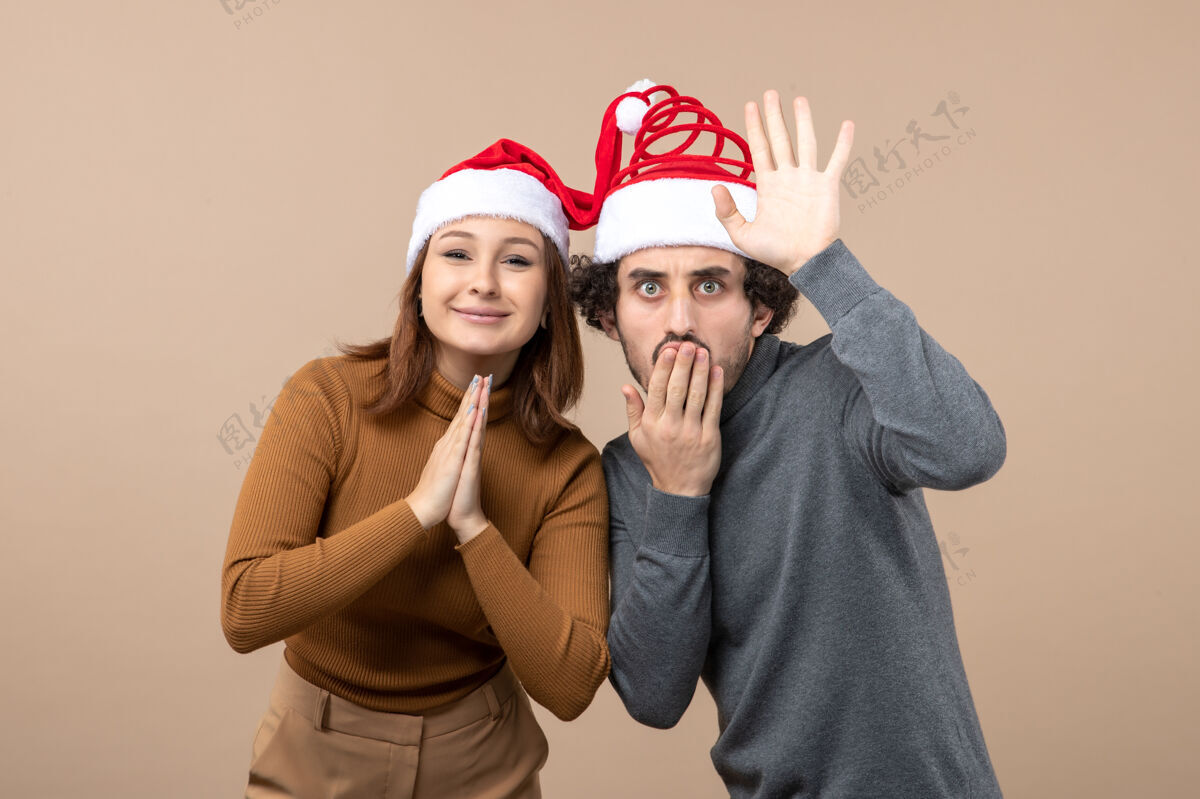 帽子新年气氛和派对理念-年轻兴奋可爱的情侣戴着灰色圣诞老人帽互相团结头盔聚会男人