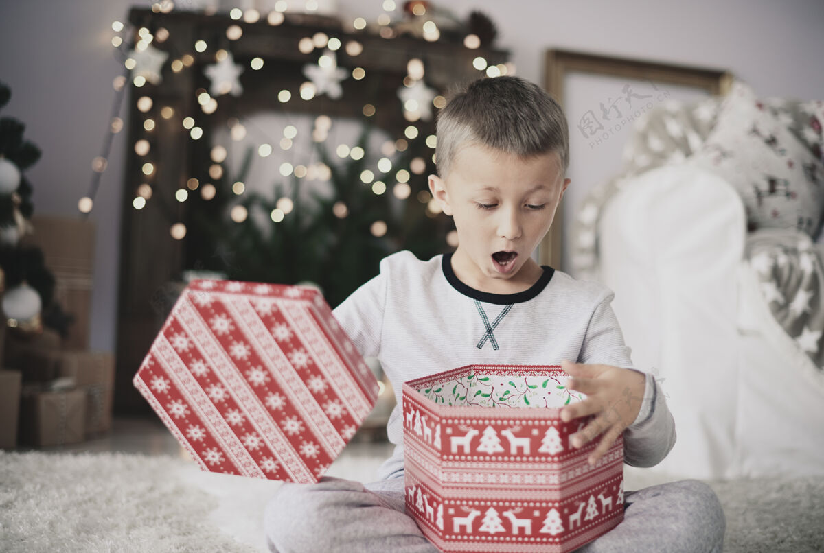 庆祝男孩在家里打开圣诞礼物凝视地板接收