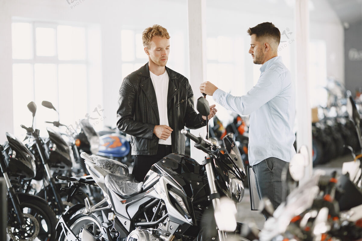 客户男人在摩托店里选摩托车穿黑色夹克的家伙经理和客户在一起摩托车交易摩托车手