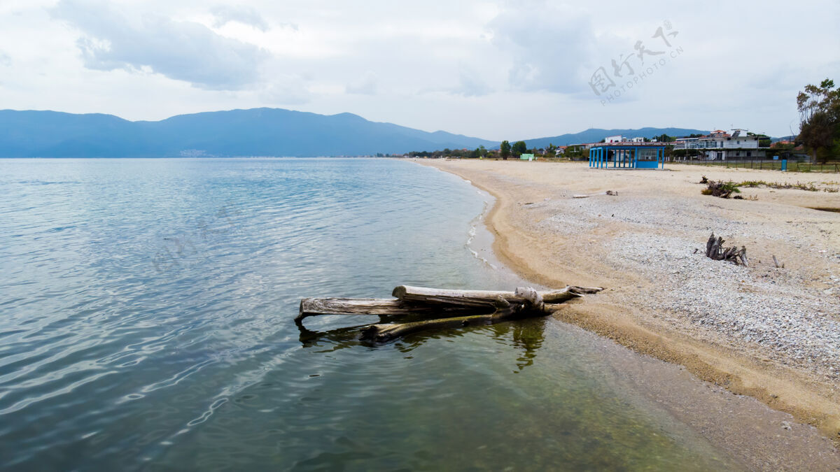 海滩海滩上枯死的树干 爱琴海海岸 建筑物和小山 阿斯普罗瓦塔 希腊度假景色石头