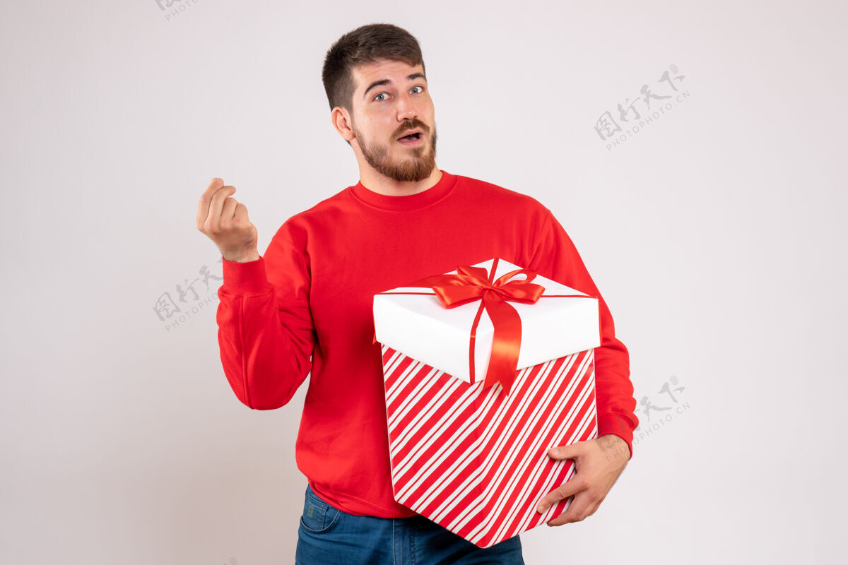人前视图中的年轻人在红衫举行圣诞礼物盒在白色的墙壁上人节日前面