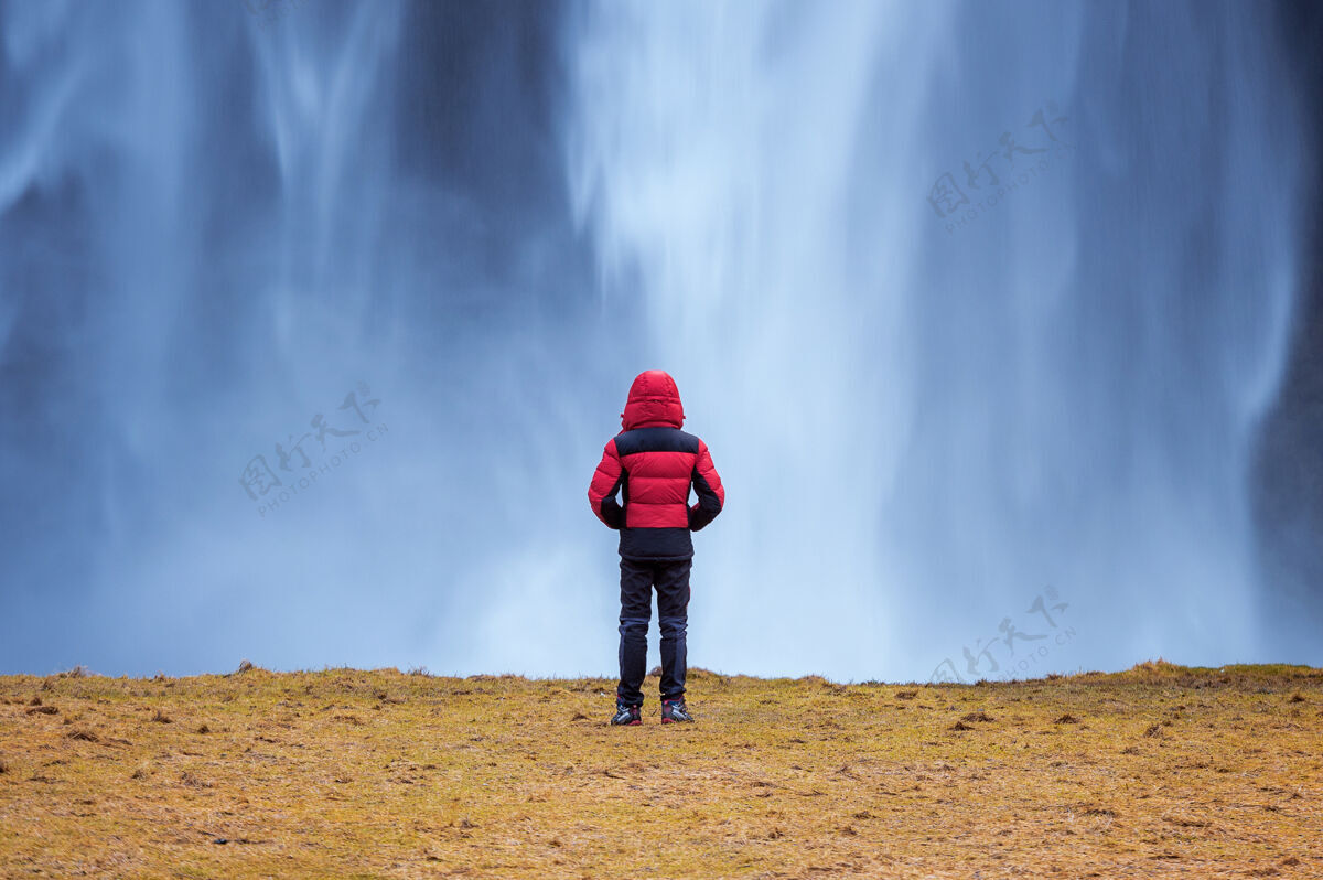 站立冰岛的塞尔加兰兹瀑布穿红色夹克的家伙看着塞尔加兰兹瀑布前面环境冰岛