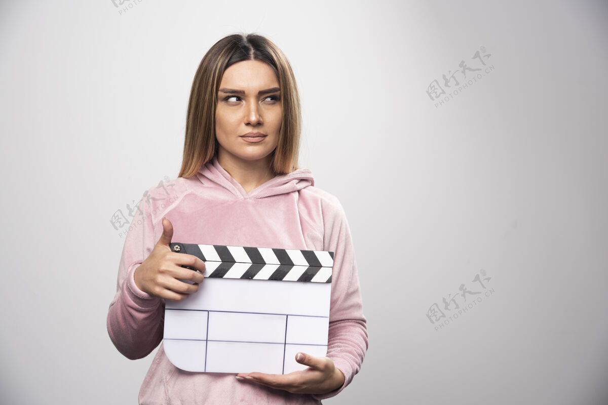 年轻人穿着粉色运动衫的金发女士拿着一块空白的隔板 摆出自然的姿势电影视频员工
