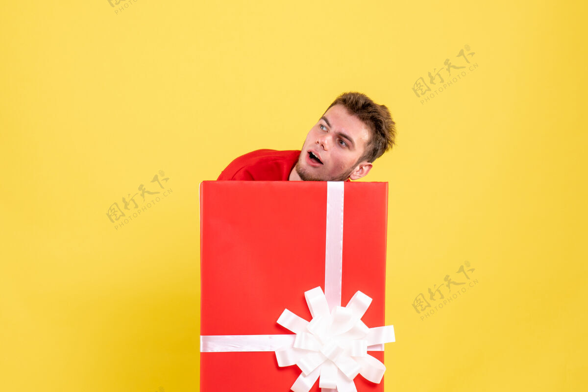 笔记本正面图年轻男子藏在礼品盒内丝带圣诞微笑