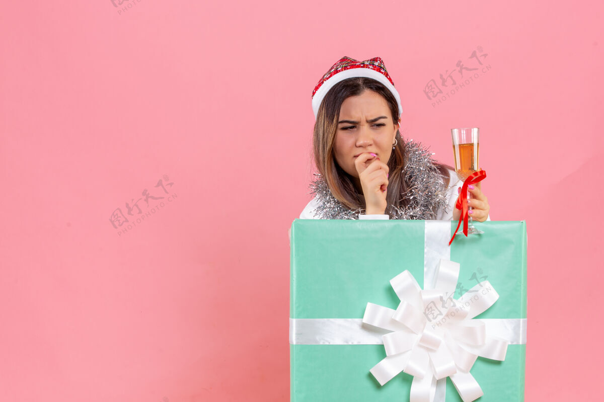 节日前视图的年轻女子庆祝圣诞节与饮料上粉红色的墙壁圣诞节年轻女性肖像