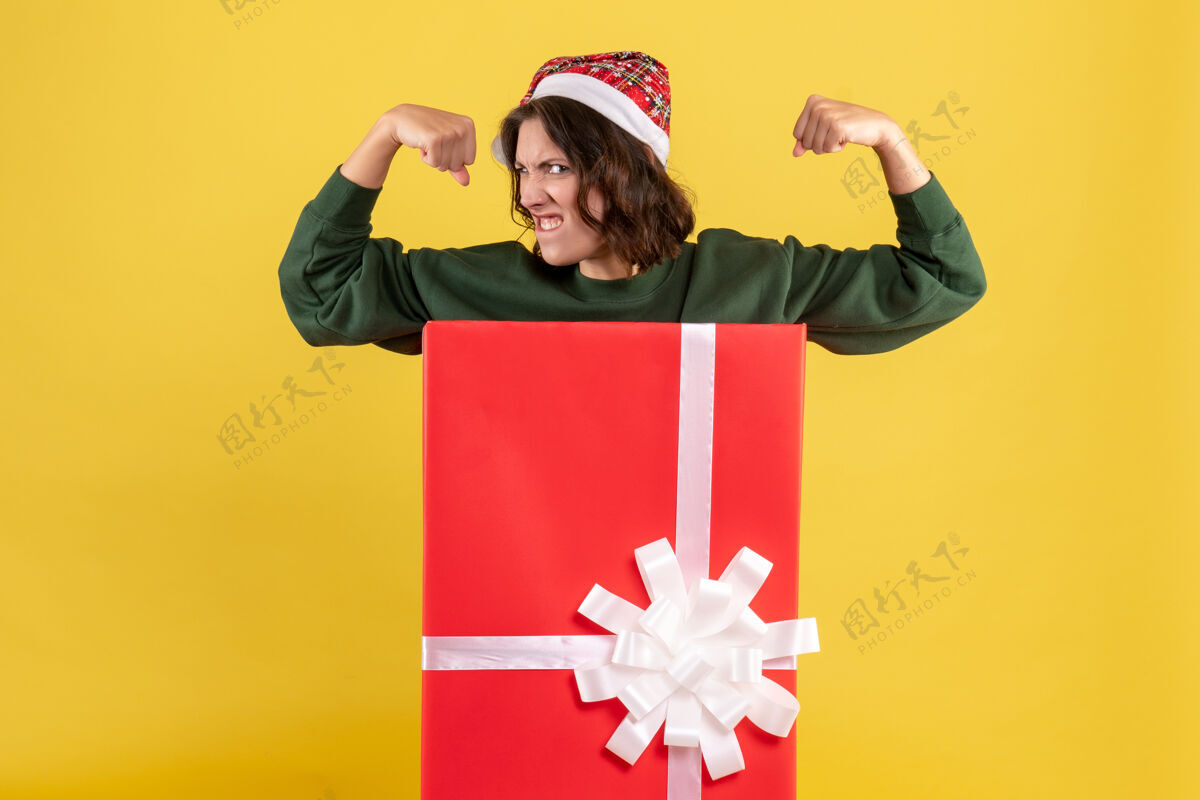 前面站在黄色墙上盒子里的年轻女子的正视图情感圣诞节节日