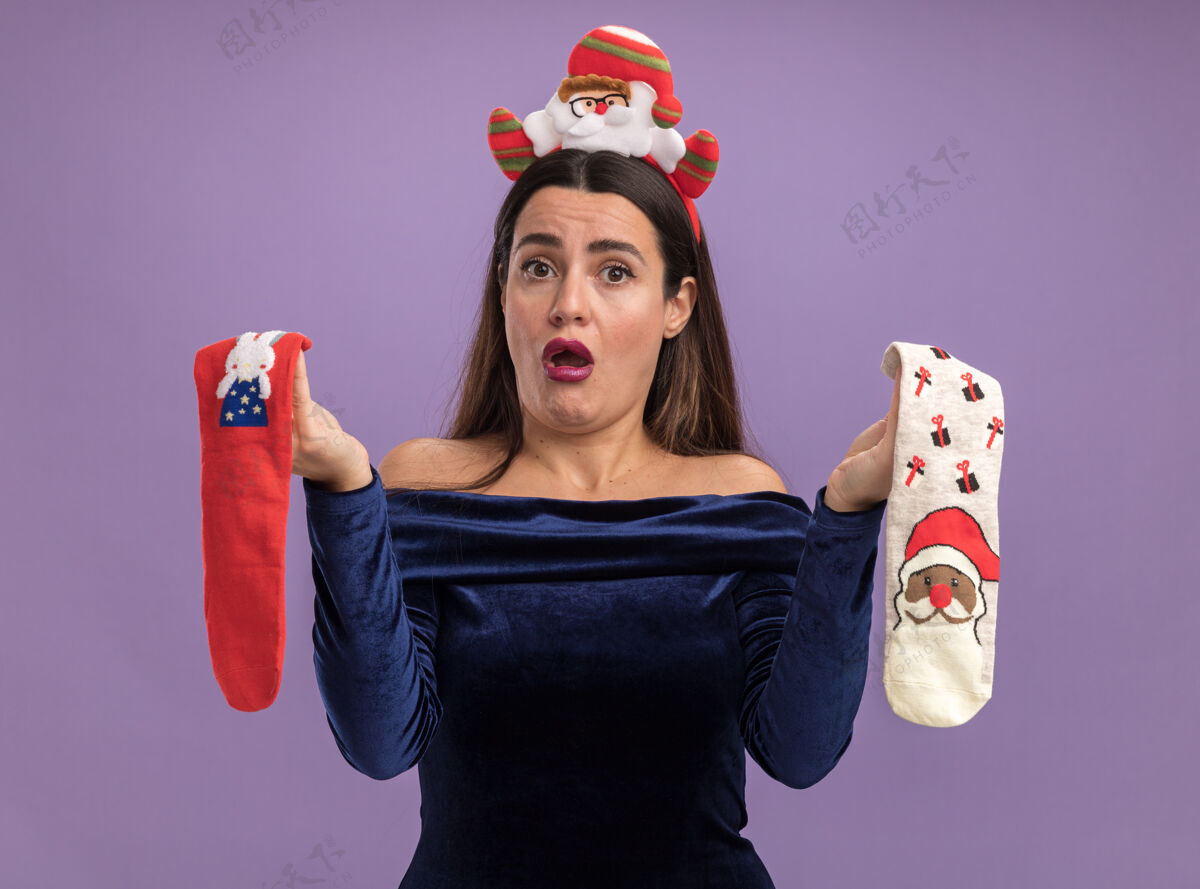 年轻人年轻漂亮的女孩穿着蓝色的裙子 戴着圣诞发箍 手里拿着圣诞袜 背景是紫色的不放袜子女孩