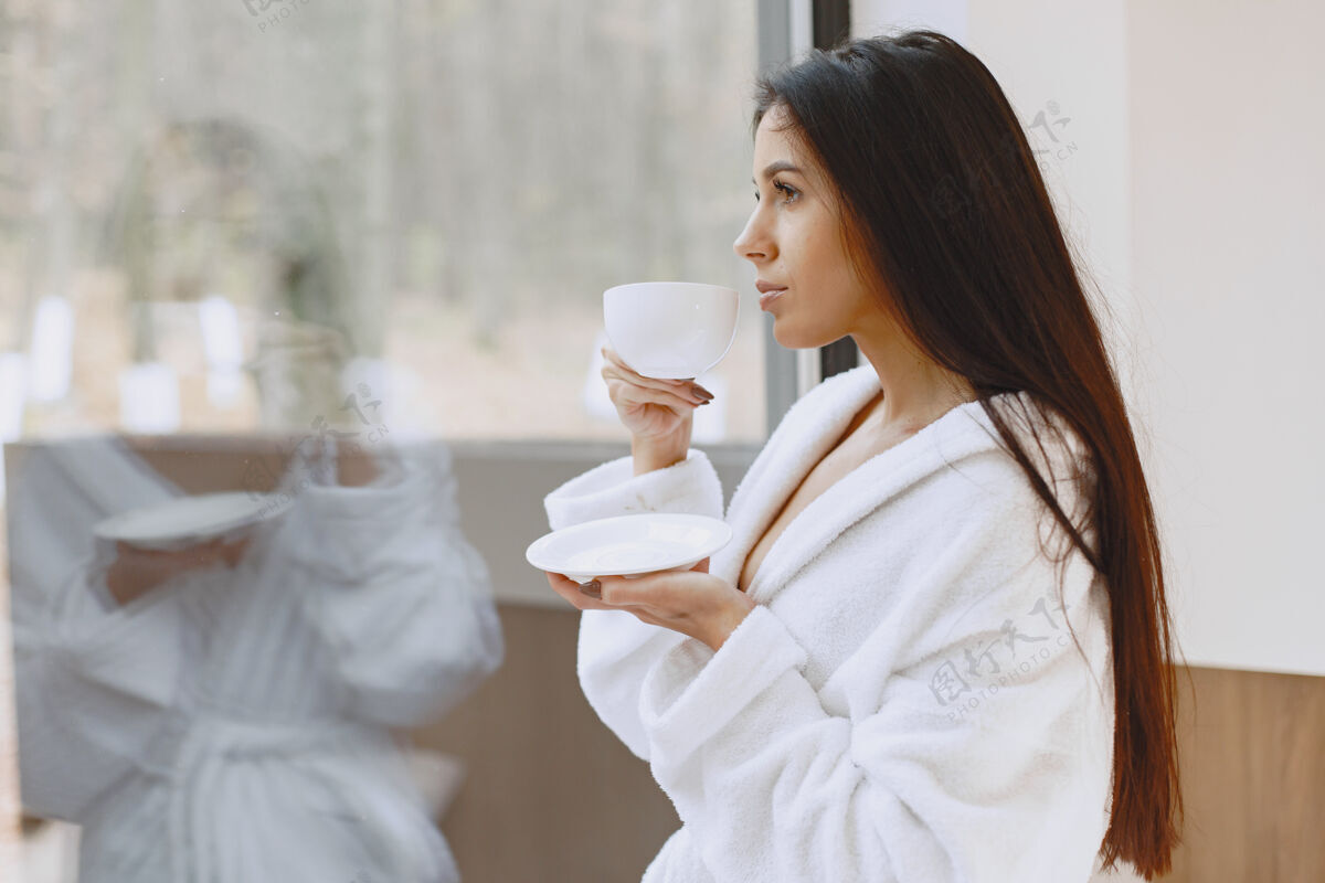 愉快早上好女人喝咖啡靠窗的女人洗澡茶打开