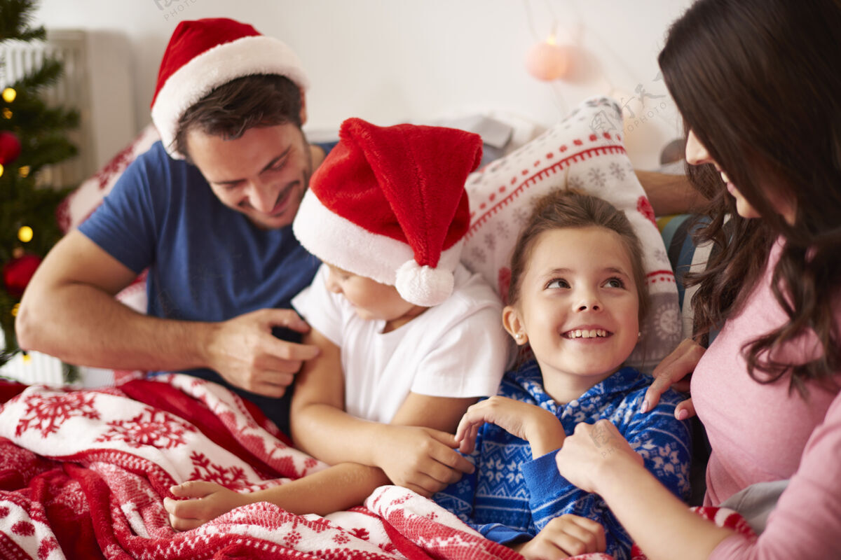 男孩和家人一起在床上度过圣诞节的早晨女儿孩子微笑