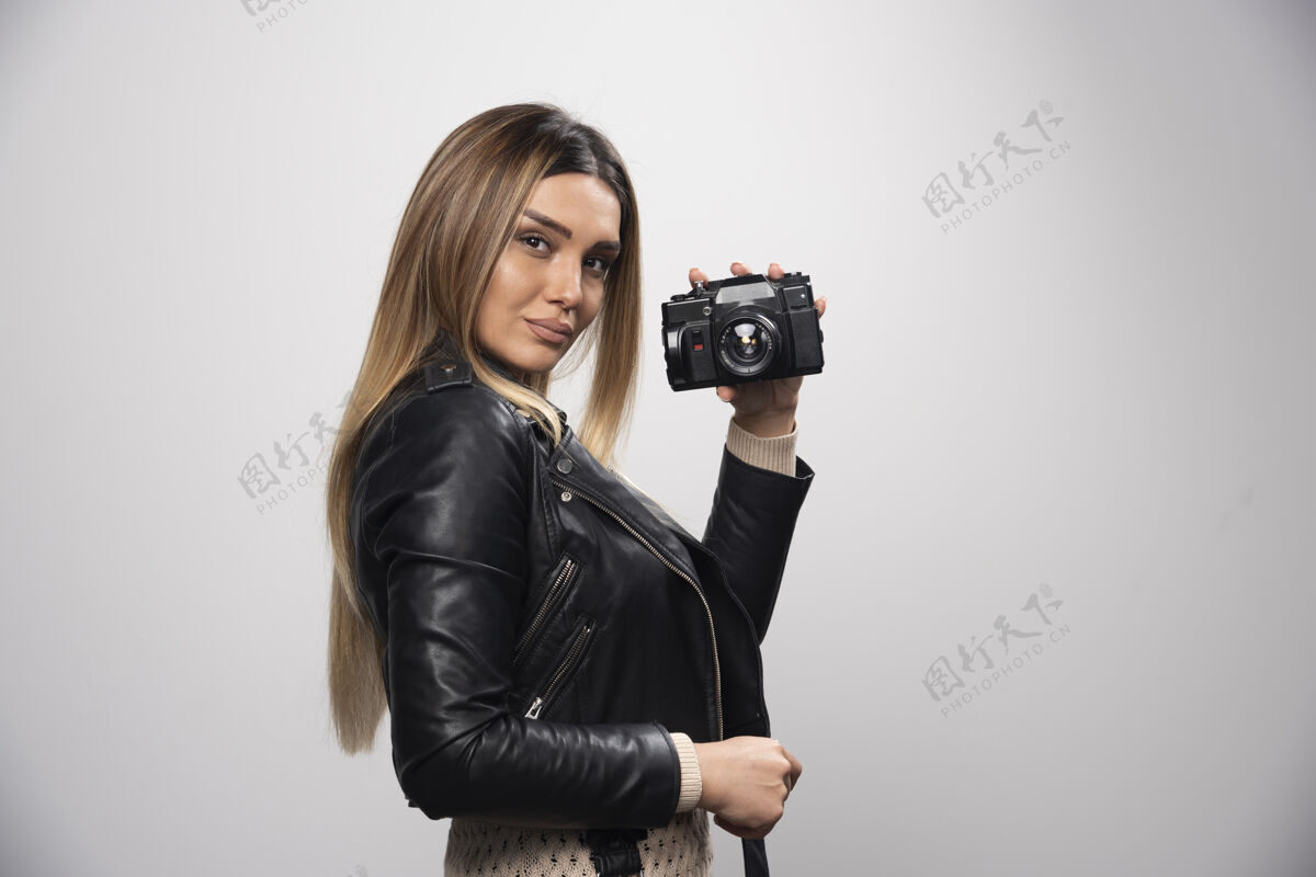 摄影师穿着皮夹克的女孩以优雅而积极的姿势拍照年轻摄影人