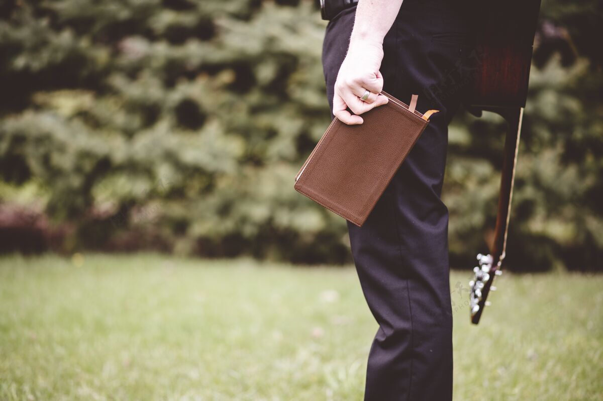 音乐一个男人在公园里背着一把吉他 手里拿着一本笔记本银播放器视图