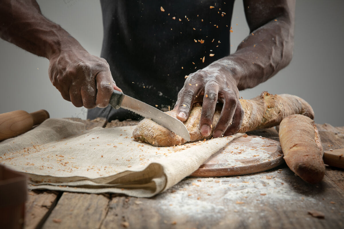 人非洲裔美国人用菜刀切新鲜面包的特写镜头人刀食物