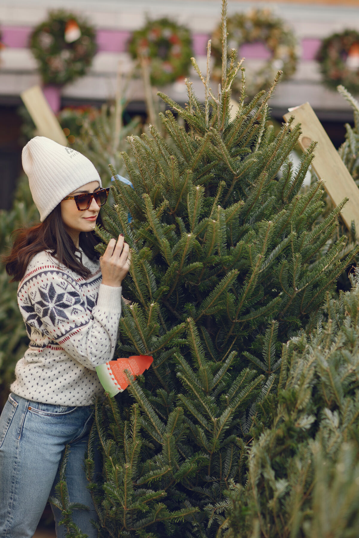 销售优雅的女孩买了一棵圣诞树传统帽子毛衣