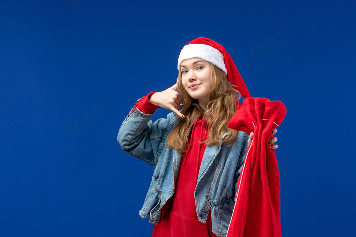 艺人前视图年轻女性拿着蓝色背景圣诞假期情感礼物包年轻女性女性前面
