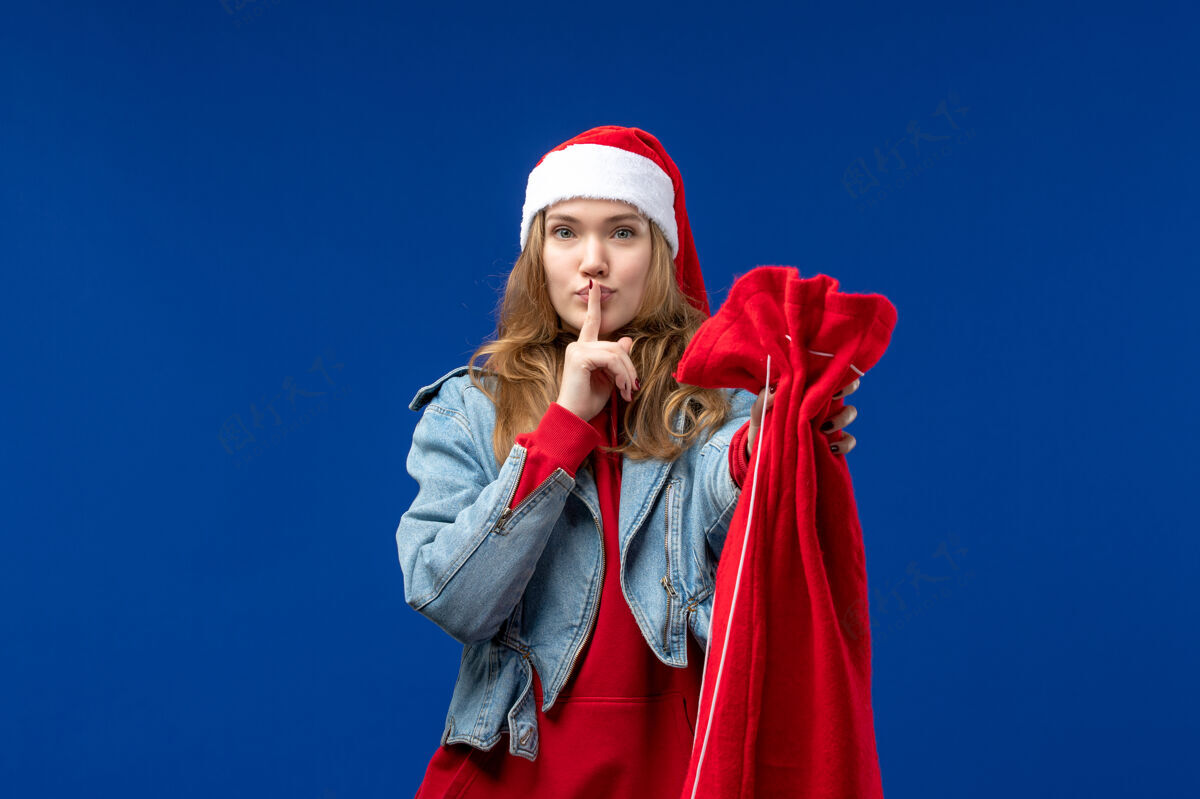 人物正面图年轻女性拿着礼物包在蓝色背景上过圣诞节头发情感音乐家