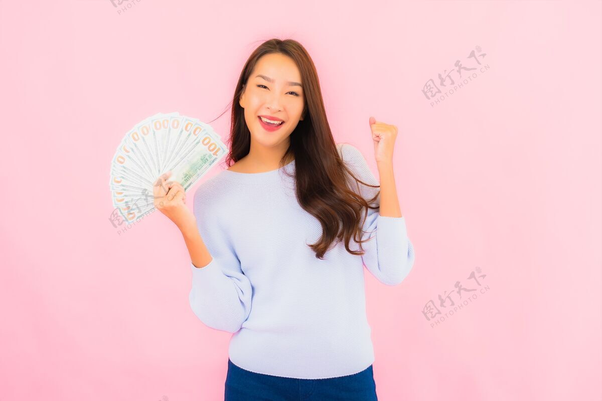 成本在粉红色的墙上画一幅美丽的亚洲年轻女子的画像 上面有很多现金和金钱投资赢成功