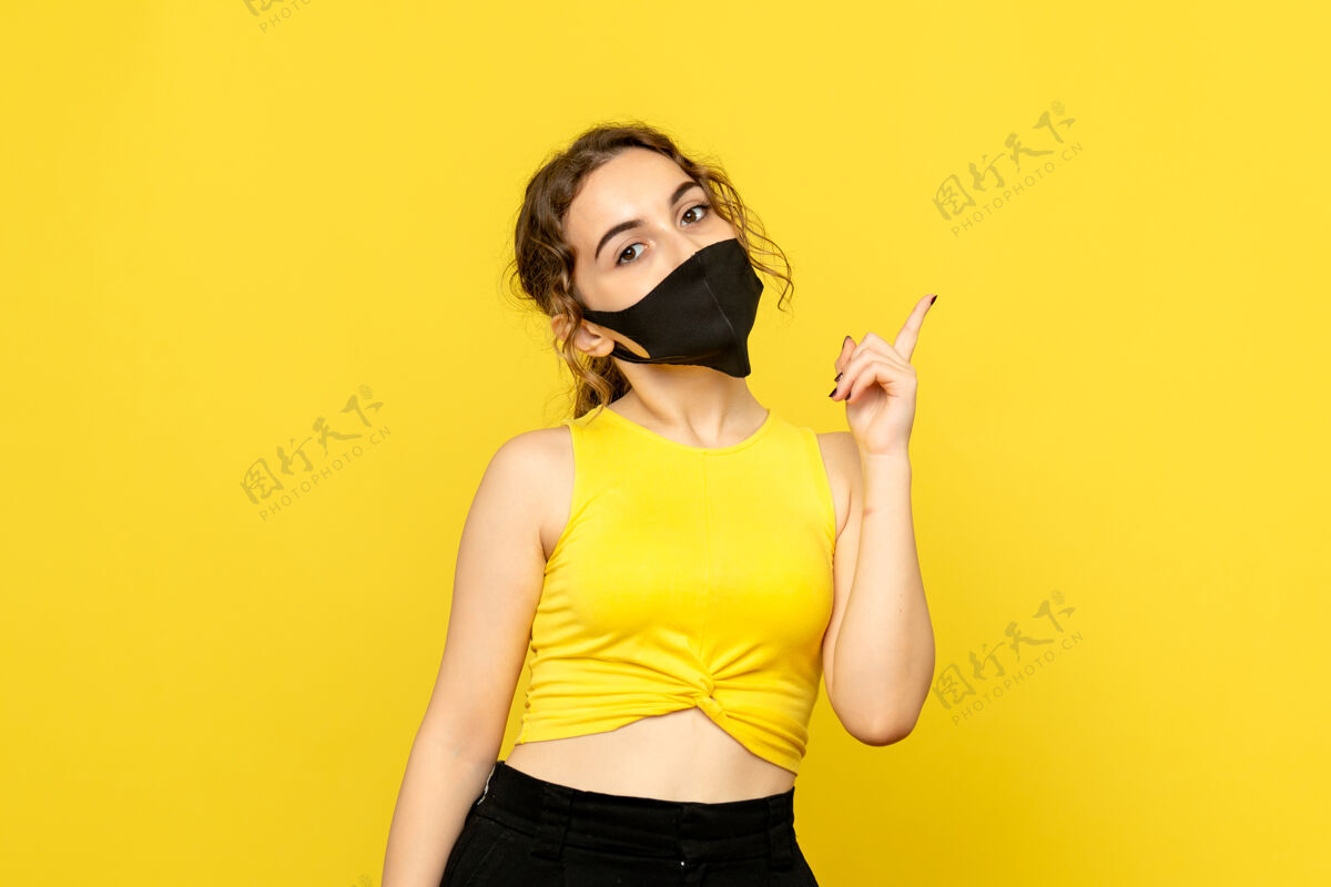 头发黄墙上戴着黑面具的年轻女子的正视图人情感可爱