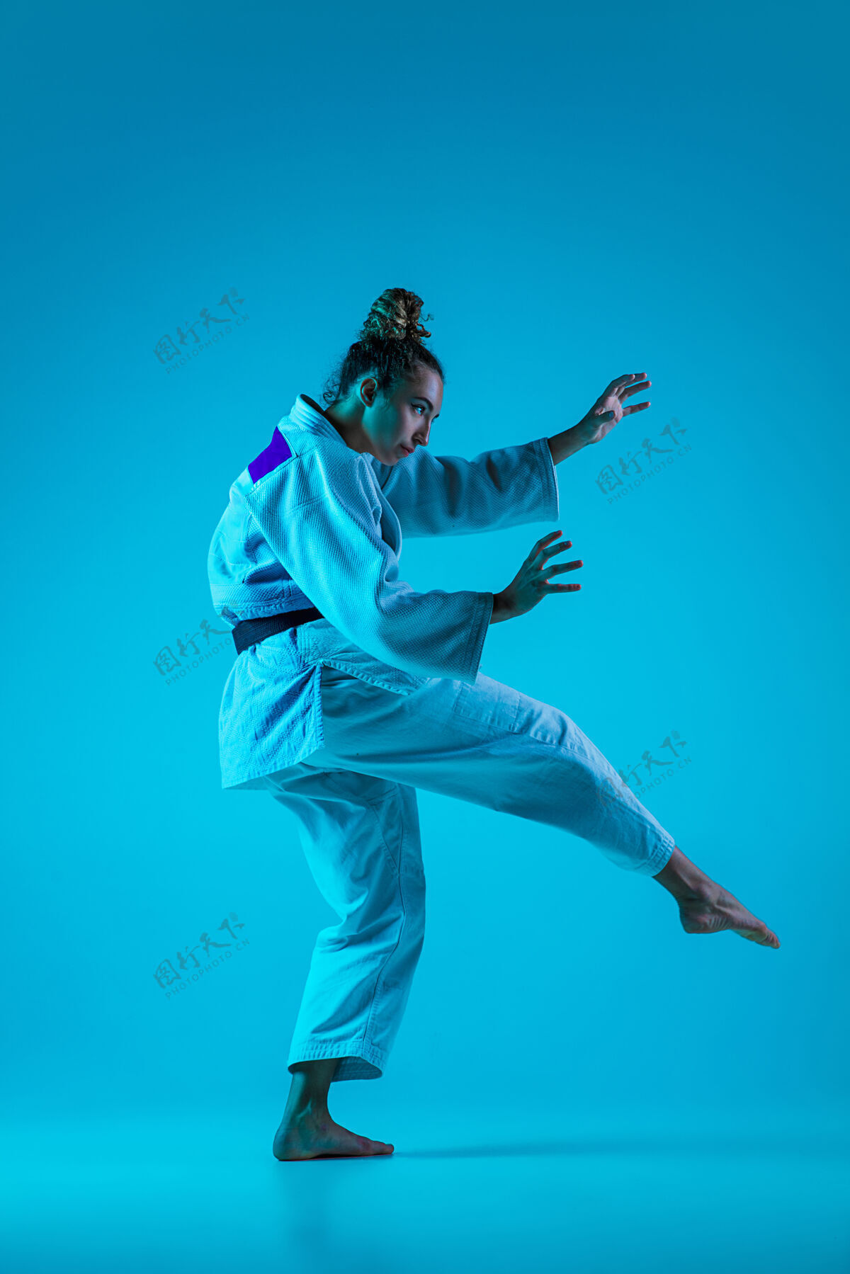 霓虹灯积极训练专业女柔道手穿着白色柔道和服 在蓝色neoned工作室背景下练习和训练游戏优雅无缝