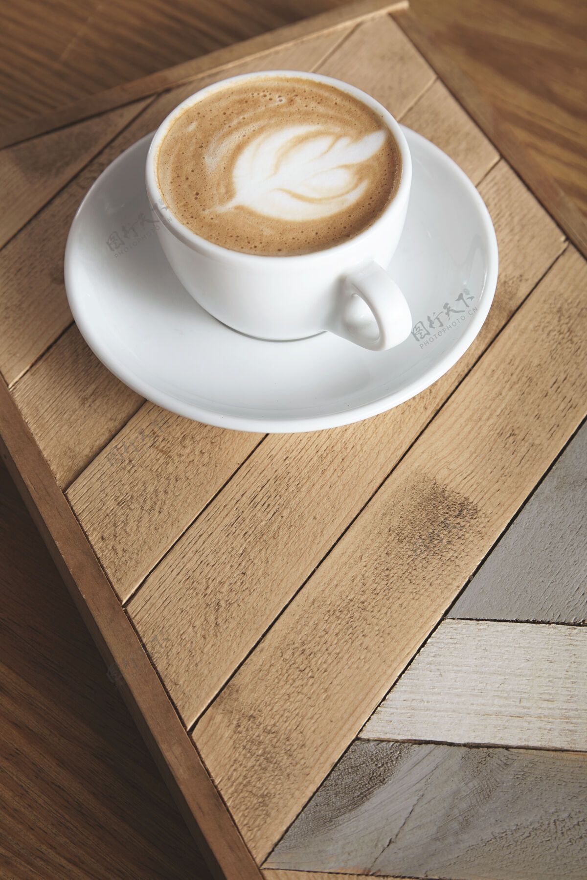 浓缩咖啡茶杯侧视图 奶油卡布奇诺拿铁 顶部有乳白色泡沫 叶形 木盘上有图案咖啡厅展示桌上有自动售货机热的咖啡