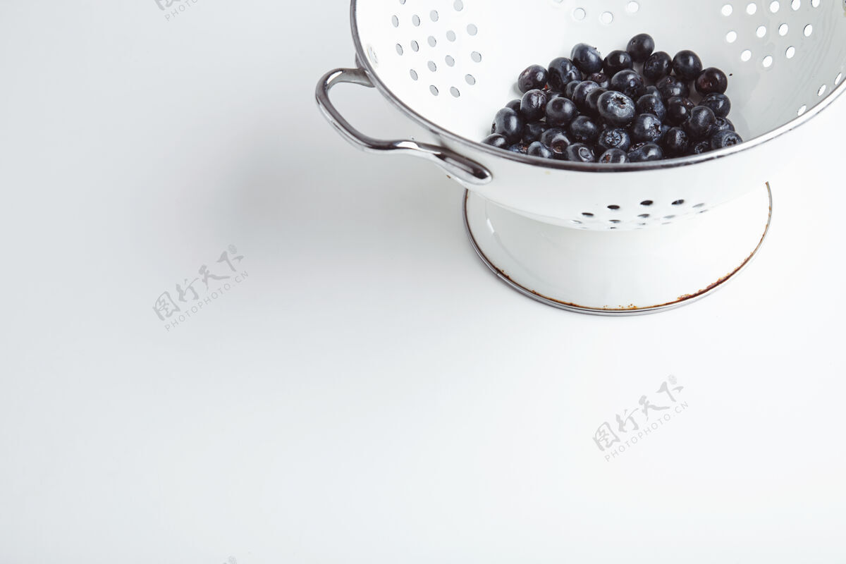 水果一堆新鲜的蓝莓放在旧的搪瓷染色机里 洗净后即可食用美味的超级食物 是清淡早餐的理想选择隔离在白色的桌子上自然碗物体