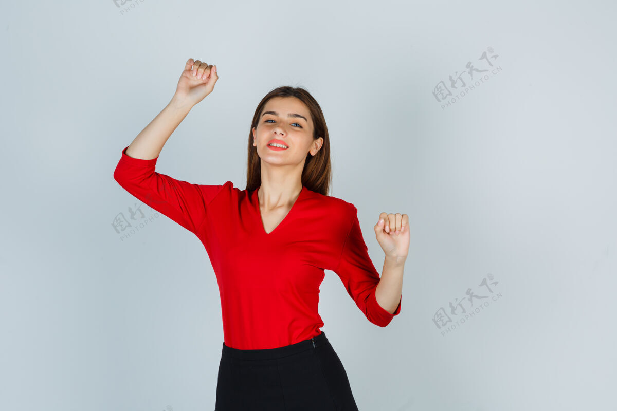自由身着红色上衣的年轻女士展示赢家姿态的肖像放松幸福跳跃