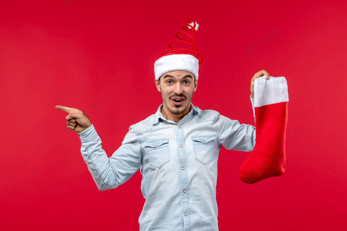 帽子前视图的年轻人与圣诞袜子摆在红墙正面男人服装