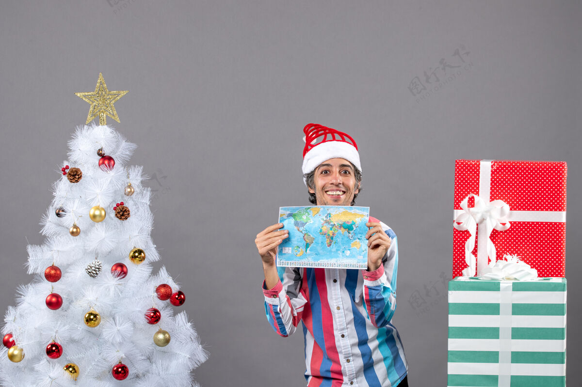 春天正面图微笑的男子戴着螺旋弹簧圣诞帽双手捧着世界地图举行假期长袜