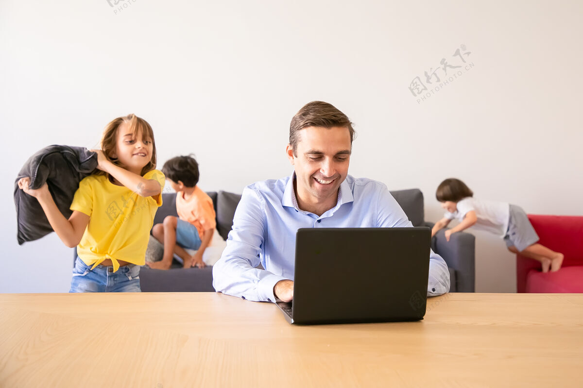 童年快乐的爸爸通过笔记本电脑聊天 孩子们在他身边玩枕头高加索父亲在学校假期在家工作家庭和数字技术概念生活男孩朋友