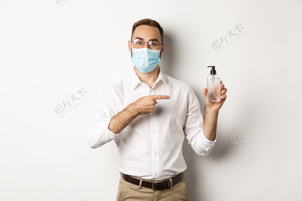 老板戴着医用口罩的上班族指着洗手液 露出抗菌的白色背景企业家衬衫自信