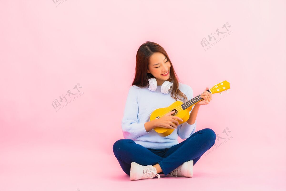 可爱的女孩肖像美丽的亚洲年轻女子在粉红色的隔离墙上演奏四弦琴泰国四弦琴音乐