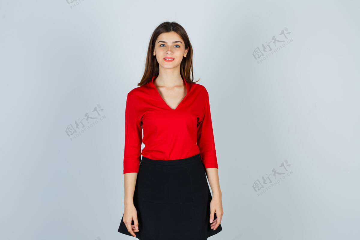 年轻年轻的女士站直了 穿着红衬衫 黑裙子 看起来很欢快肖像女人人