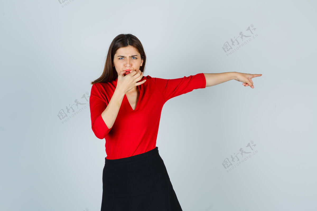 不安年轻的女士吹着口哨 用食指指着右边的红色上衣严重情绪愤怒