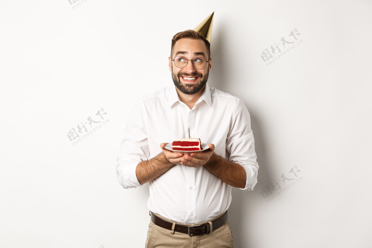 兴奋节日和庆祝快乐的男人有生日聚会 在生日蛋糕上许愿 微笑着 站着庆祝帽子休闲