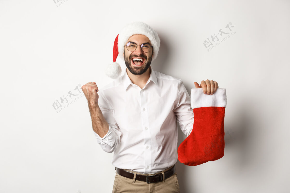 圣诞节圣诞快乐 节日概念快乐的成年人收到礼物在圣诞节袜子 看起来很兴奋 戴着圣诞帽庆祝微笑开朗