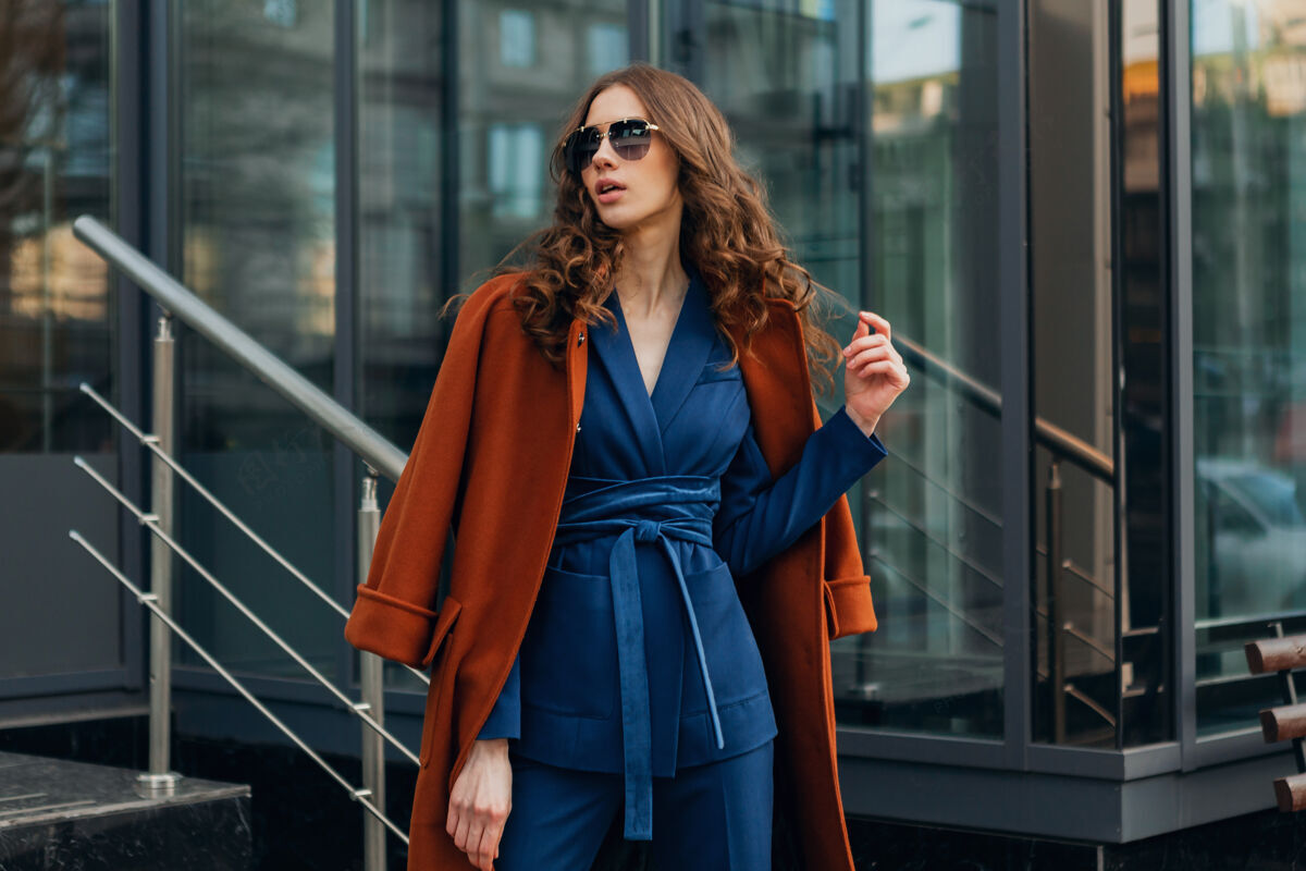 优雅可爱时尚的女人带着走在都市商业街上的温暖棕色外套和蓝色西装 春秋时尚的街头风 戴着墨镜西装优雅服装