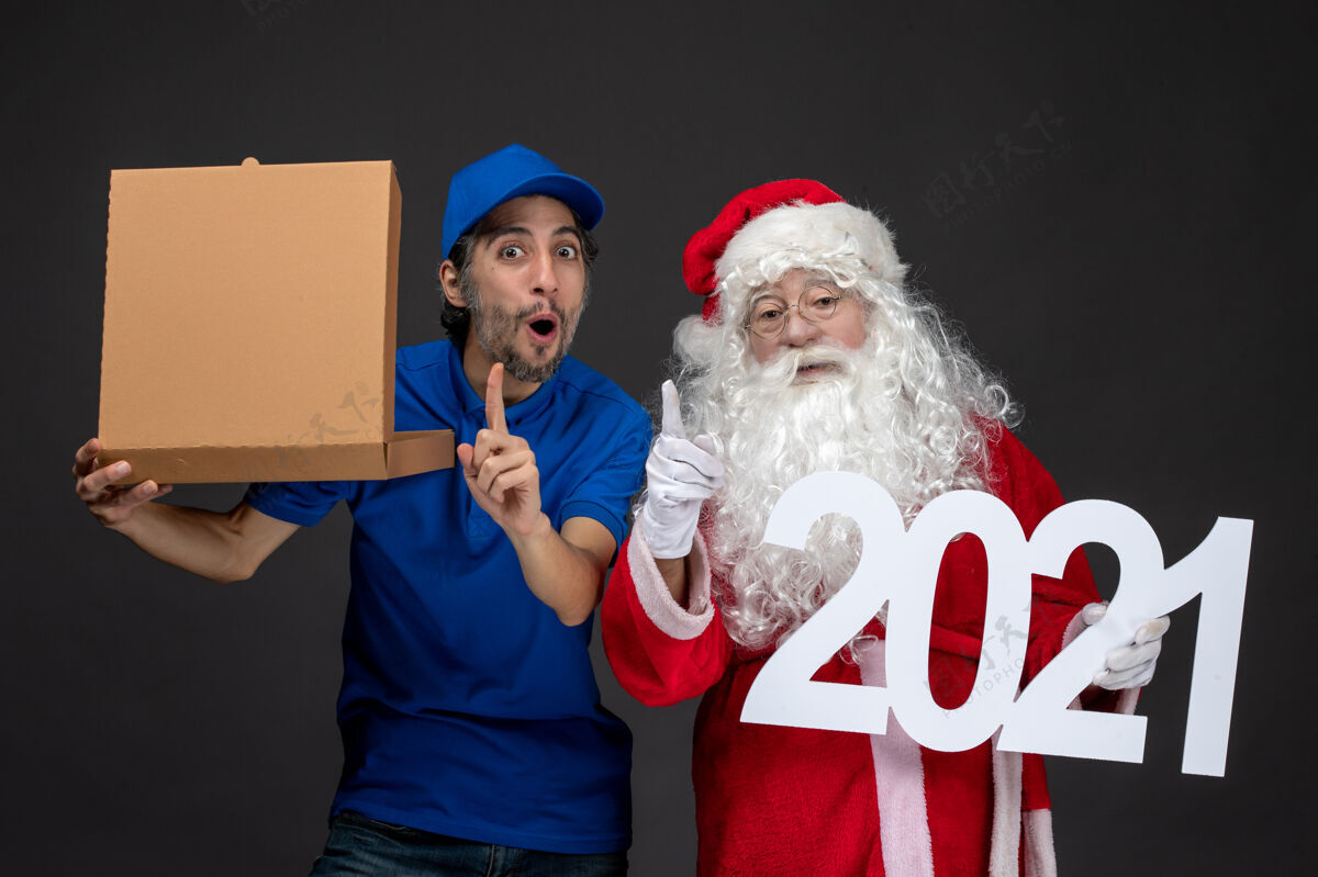 快乐圣诞老人的正面图 男信使拿着食物盒 在黑暗的墙上黑暗男性举行