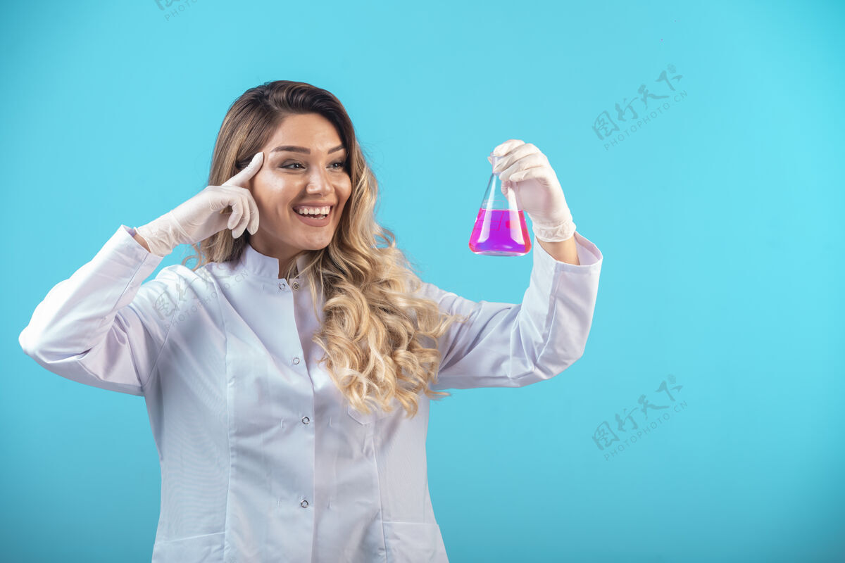 从业者穿着白色制服的护士拿着一个装有粉红色液体的化学瓶疾病测试临床