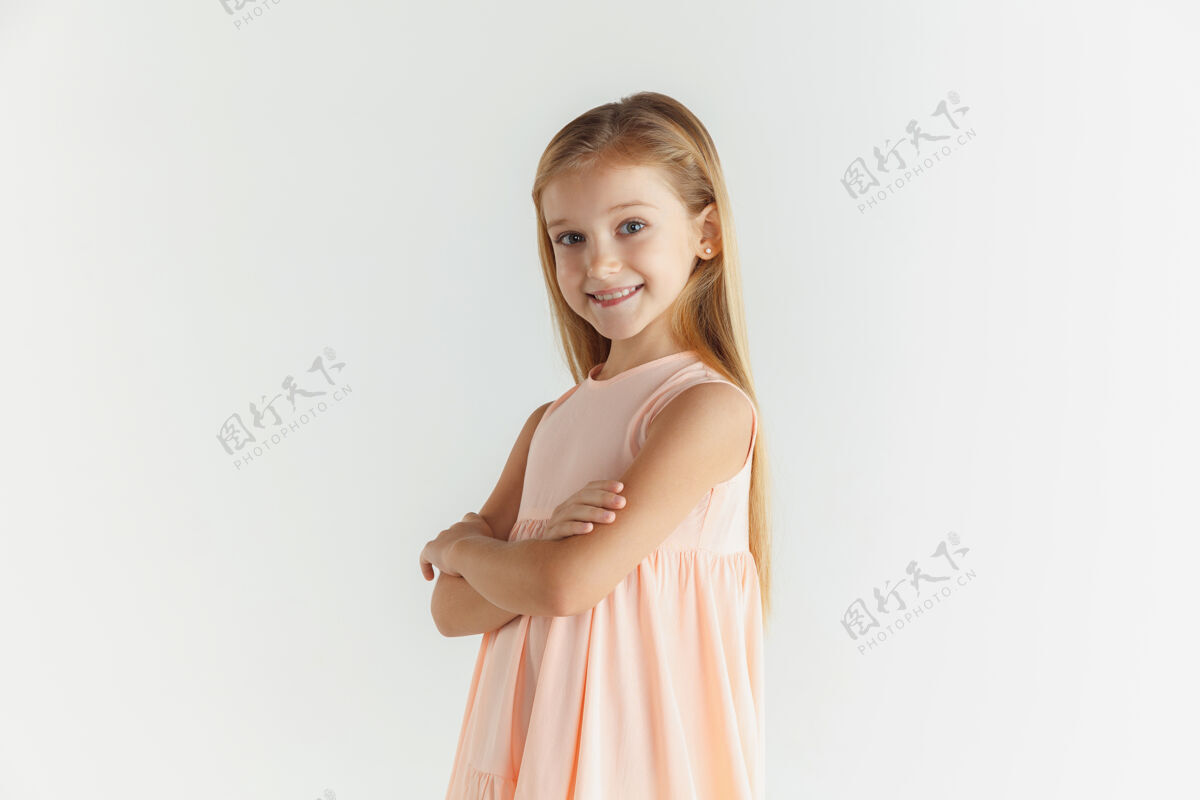 活动时尚的微笑小女孩在白色工作室里穿着隔离的裙子摆姿势自信开朗服装