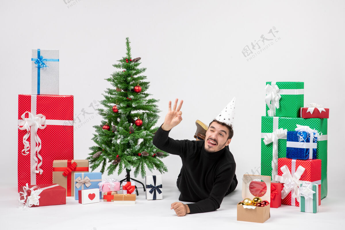 情感年轻人躺在白色墙上的节日礼物周围的正面视图圣诞节日人
