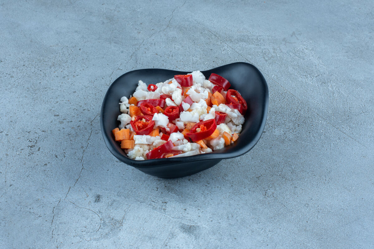 胡椒用花椰菜 胡椒和胡萝卜做成的沙拉 放在大理石上的黑色碗里沙拉蔬菜午餐